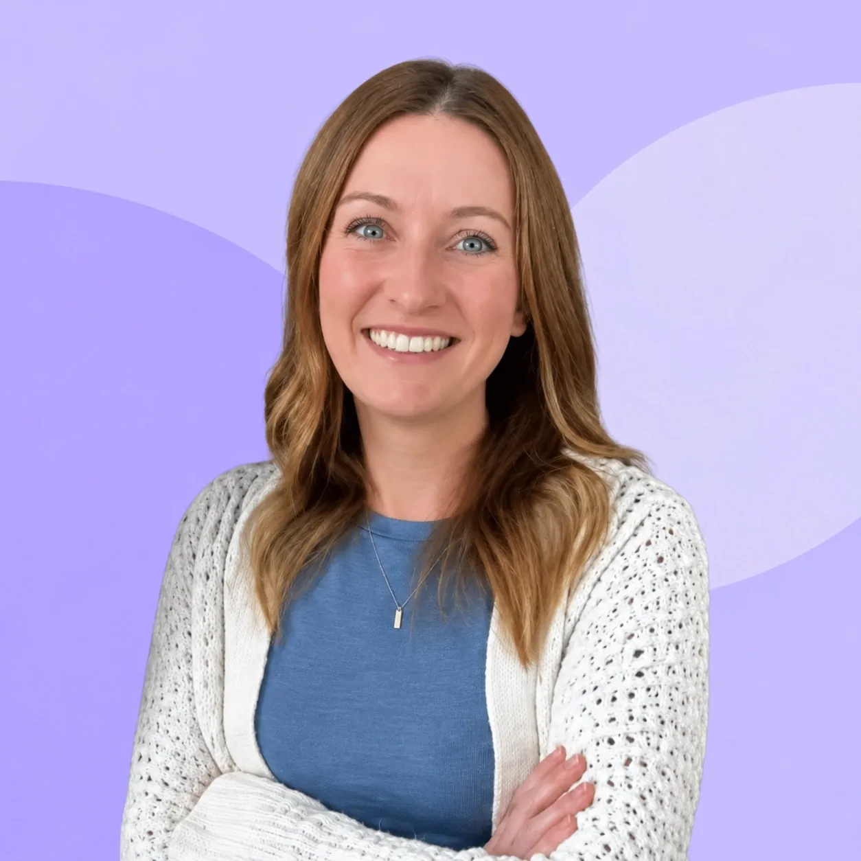 Emily Moran, smiling, in a white cardigan over a blue top, against a pale lilac background.
