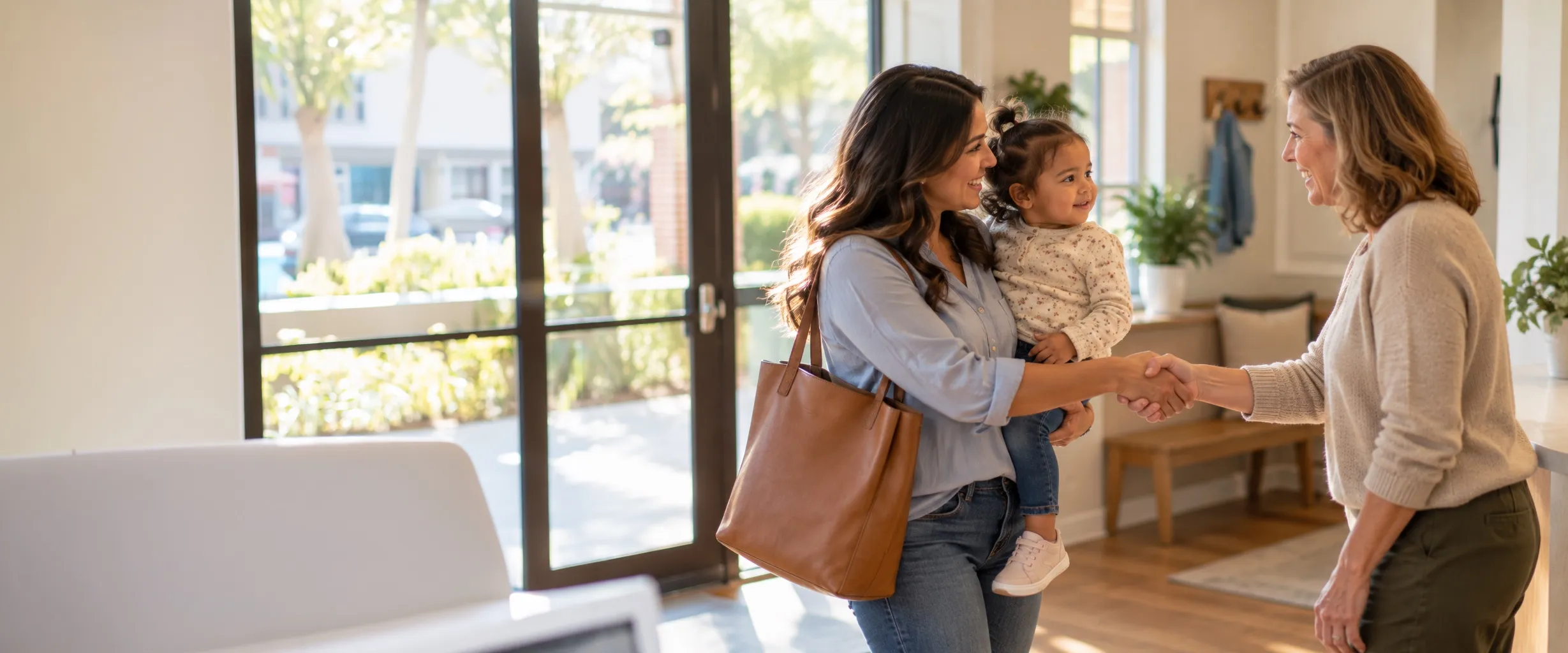 A pediatrician welcomes a mother and her toddler at the office entry.
